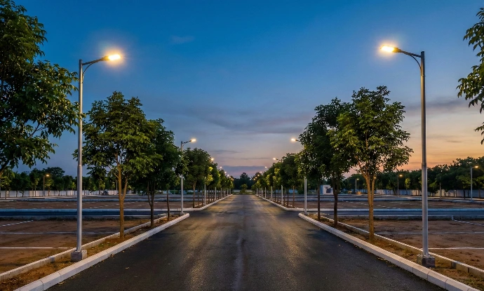 Wide internal asphalt roads with LED street lights and tree plantation in a plotted development project.
